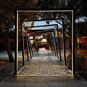 Lit steel frames stepping down a patterned walkway at Elevado.
